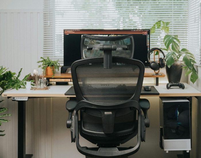 A minimalist home office setup featuring a sleek ergonomic chair, desk, and monitor.