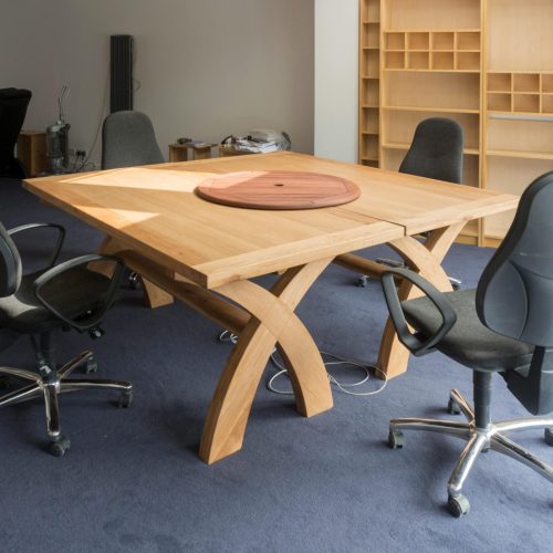 Contemporary office meeting room featuring a unique wooden table design and ergonomic chairs.